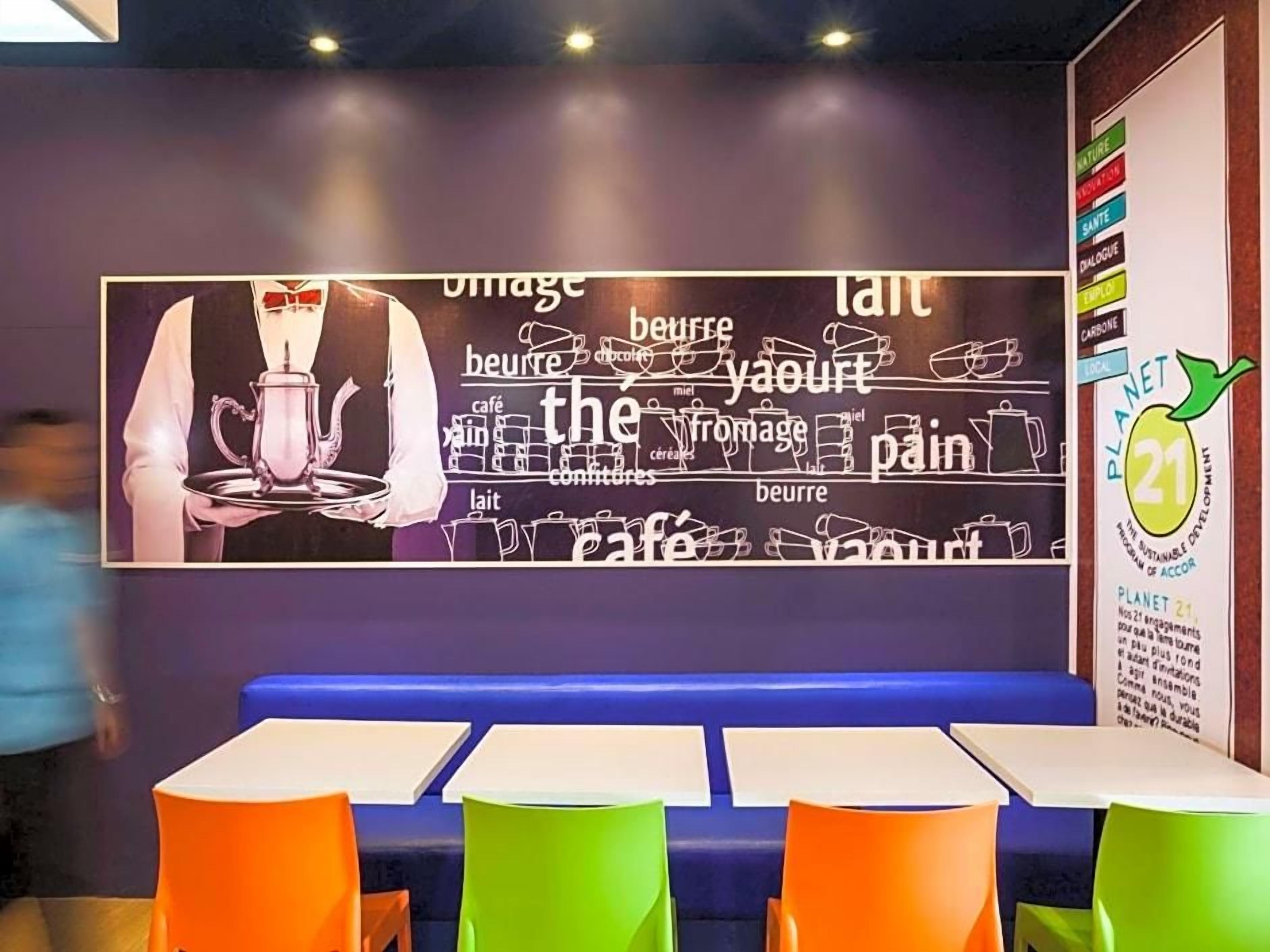 Een restaurantinterieur met een wand waarop woorden over eten staan en een Planet 21 logo.