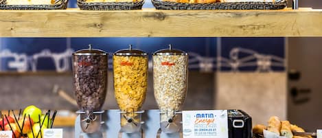 Un bufé de desayuno con cereales, fruta, una máquina de café y un cartel que indica desayuno 'MALIN Energy'.
