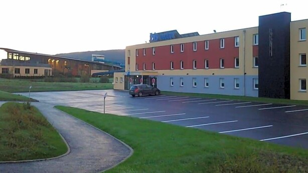 A parking lot with a building in the background. - Ibis Budget Givet (Givet)
