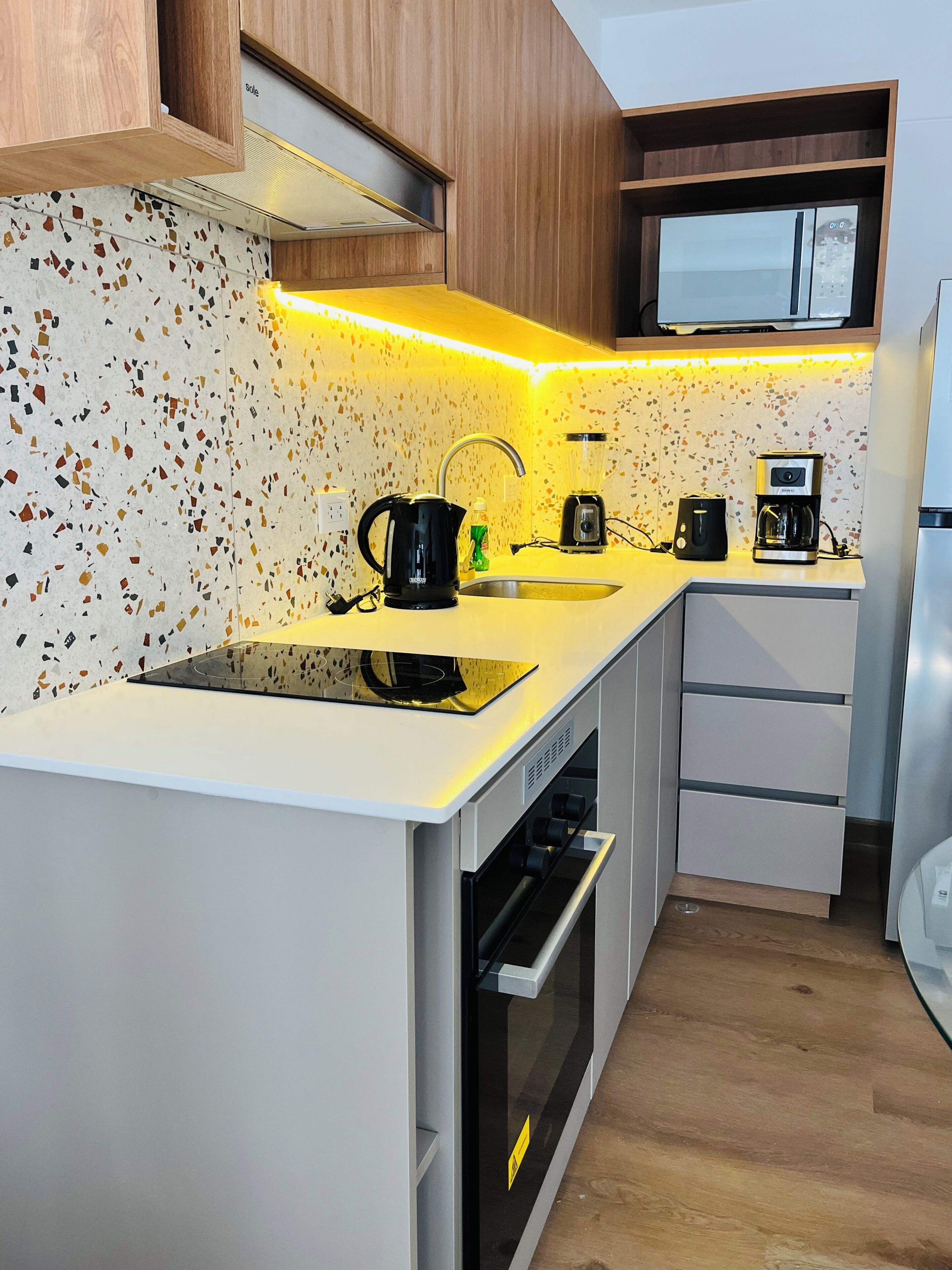 Een moderne keuken met een aanrecht, gootsteen, fornuis, oven en een magnetron.