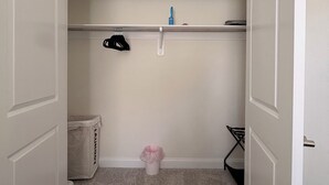 Un espai petit i tancat amb una barra penjant, un cubell de brossa i una cistella de roba.