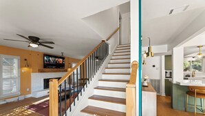 Eine Treppe mit Holzbodenstufen und schwarzen Geländern, ein Deckenventilator und ein Kamin.