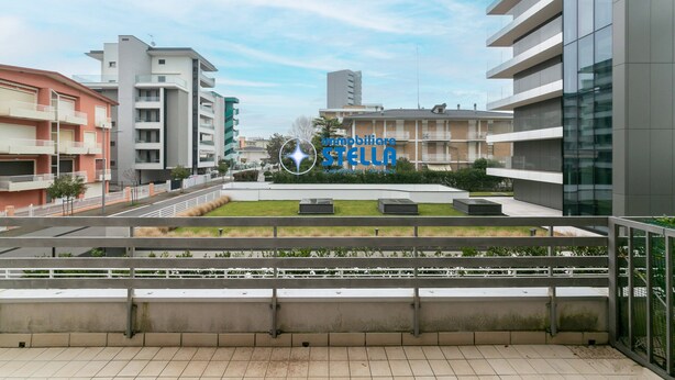 Un quartier résidentiel urbain moderne, avec des immeubles à plusieurs étages, un espace central ouvert doté de sièges et un ciel dégagé.