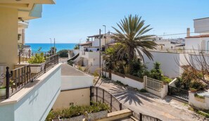 A residential street with a view of the sea, white houses, and palm trees. - House Elena - Ground Floor (Torre San Giovanni)