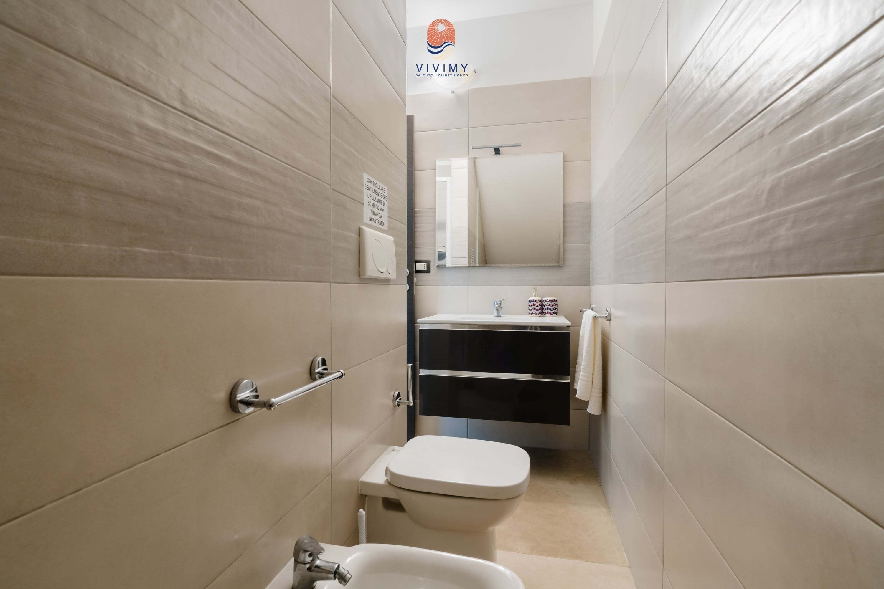 Un baño moderno con inodoro, lavabo y espejo.