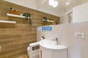 Ein modernes Badezimmer mit einer Holzwand, einem weißen Waschbecken und einem Spiegel.