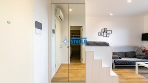 Una sala de estar moderna con un sofá, un televisor de pantalla plana y una escalera que lleva a un dormitorio.