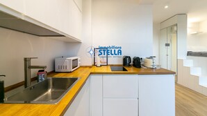 Una cocina moderna con un lavamanos de acero inoxidable, un microondas, una tetera y un tostador.