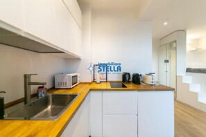 Eine moderne Küche mit Spüle aus Edelstahl, einer Mikrowelle, einem Wasserkocher und einem Toaster.