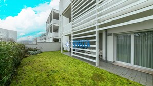 Un edificio moderno con fachada blanca, un patio con césped y el logotipo de 'immobiliare STELLA'.