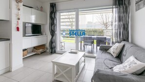Una sala de estar moderna con un sofá, una mesa de centro, un televisor y un puerta corrediza de vidrio a un espacio exterior.