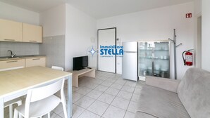 A modern kitchen with a dining area, a television, and a refrigerator. - Tiepolo apt. w/beach place + parking (Jesolo)