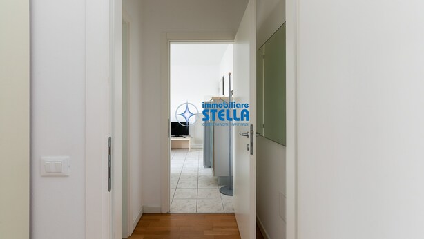 A hallway with a door leading to a room, a light switch, and a radiator. - Tiepolo apt. w/beach place + parking (Jesolo)