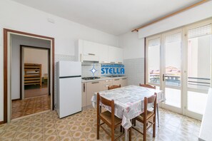 Una cucina con un tavolo da pranzo, un frigorifero e vista attraverso una porta scorrevole in vetro.