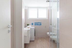 Ein modernes Badezimmer mit Dusche, Toilette und Waschmaschine.