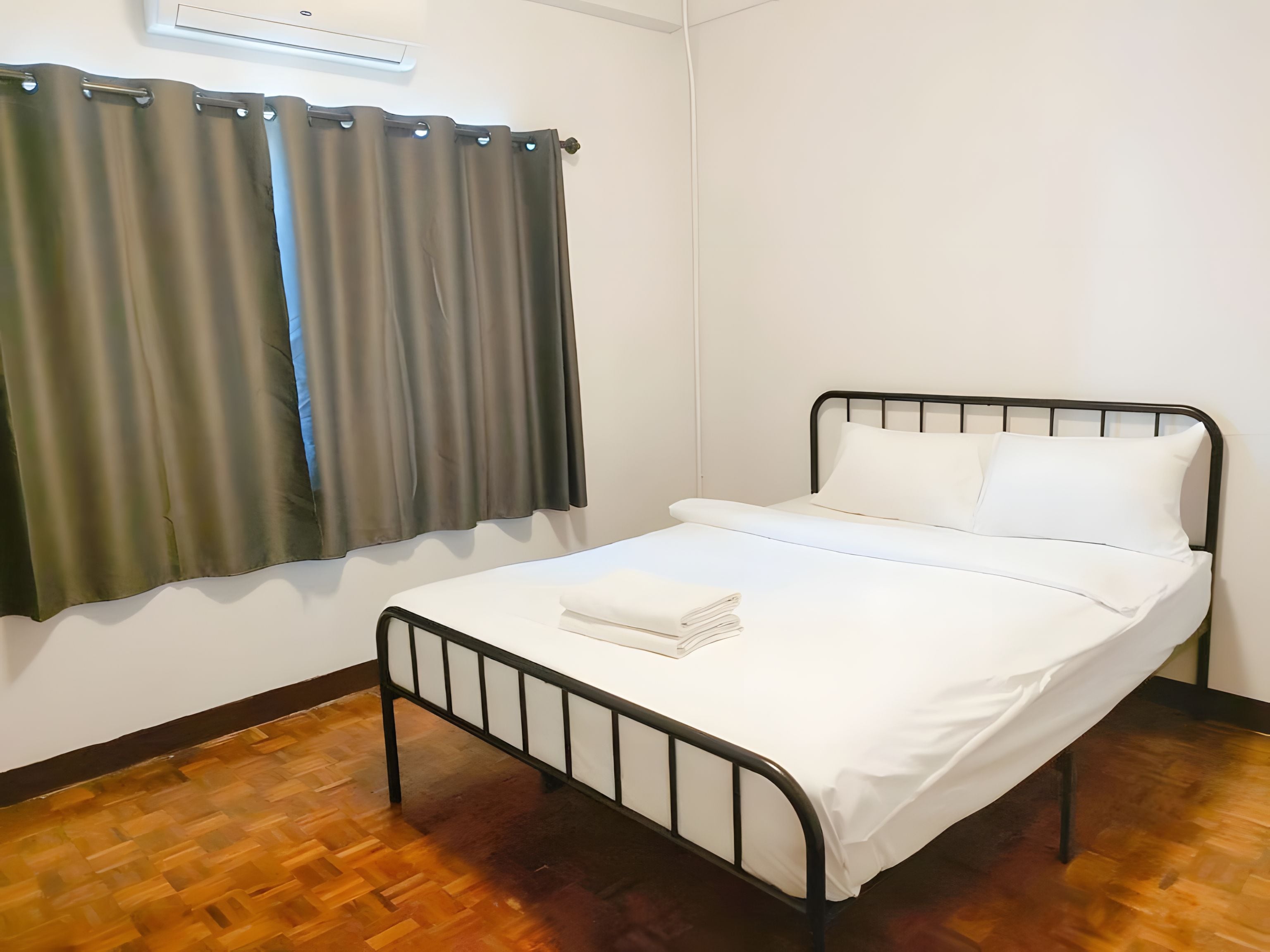 A single bed with white bedding, a metal frame, and a small bedside table with a folded white cloth.