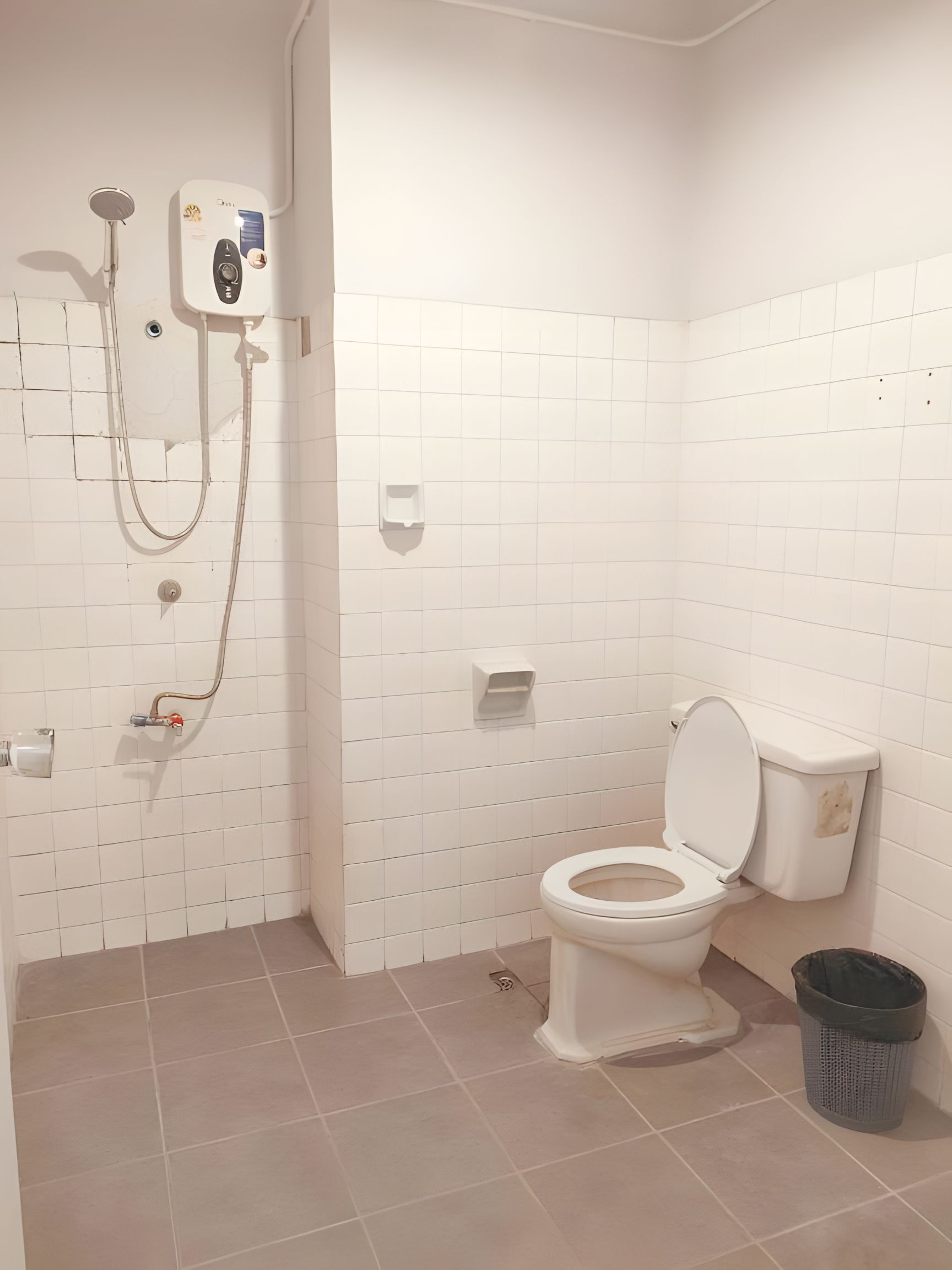 Un baño con inodoro, ducha y un cubo de basura.
