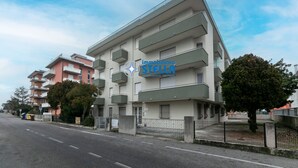 Ein mehrstöckiges Gebäude mit Balkonen, einem Schild für 'immobiliare STELLA' und blauem Himmel.