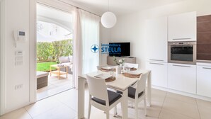 Una cucina moderna con mobili bianchi, forno a incasso e zona pranzo con tavolo e sedie.