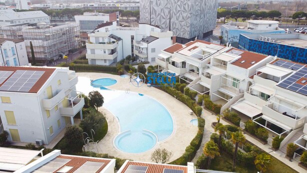 Un complesso residenziale con diversi edifici, una piscina e pannelli solari sui tetti.
