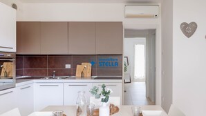 Una cucina moderna con mobili bianchi, un lavello in acciaio inossidabile e un piano di lavoro con un vaso e bicchieri.