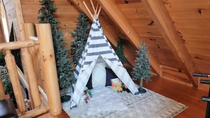 A wooden tent with a striped canopy, surrounded by small Christmas trees, on a patterned rug in a room with wooden walls and a sloped ceiling. - Amazing Grace - Two Bedroom Cabin (Sevierville)