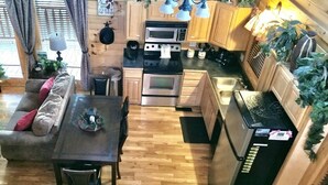 A cozy cabin-style interior with a sofa, dining table, kitchen area including a stove, microwave, and cabinets, and wooden flooring. - Amazing Grace - Two Bedroom Cabin (Sevierville)