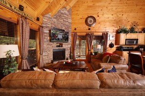 A cozy living room with a fireplace, leather sofa, and a television mounted on the wall. - Amazing Grace - Two Bedroom Cabin (Sevierville)