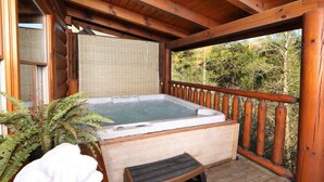 A wooden deck with a hot tub, a wooden bench, and a potted plant. - Amazing Grace - Two Bedroom Cabin (Sevierville)