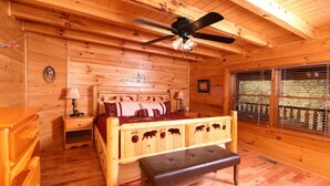 A wooden cabin bedroom with a bed, bench, ceiling fan, and window with blinds. - Amazing Grace - Two Bedroom Cabin (Sevierville)