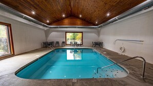 An indoor swimming pool with a wooden ceiling, clear ceiling vents, and a view of trees through a large window. - Amazing Grace - Two Bedroom Cabin (Sevierville)