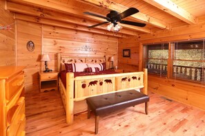 A wooden cabin bedroom with a bed, bench, ceiling fan, and window with blinds. - Amazing Grace - Two Bedroom Cabin (Sevierville)