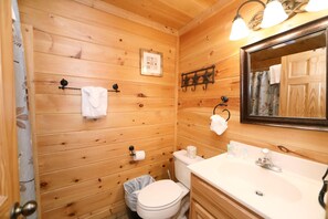 A wooden-paneled bathroom with a toilet, sink, and mirror. - Amazing Grace - Two Bedroom Cabin (Sevierville)