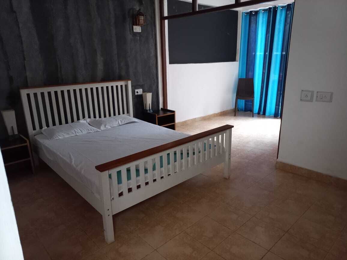 Un dormitorio con cama, mesitas de noche, un espejo y vistas al exterior.