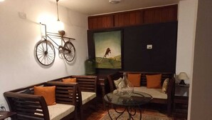Un salon chaleureux avec un canapé en bois, une table basse en verre et une œuvre d’art murale représentant un vélo.