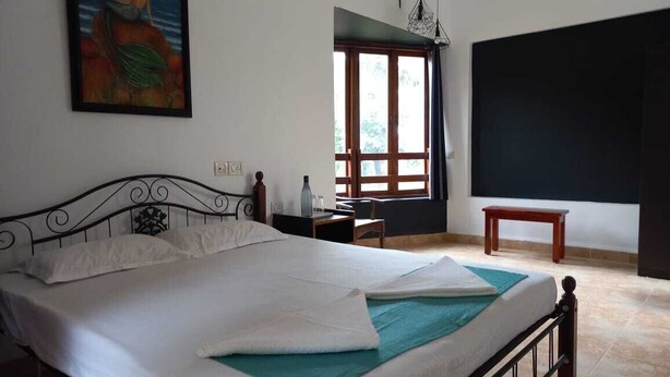 Une chambre à coucher avec un lit, un tableau au mur, une fenêtre et une porte.