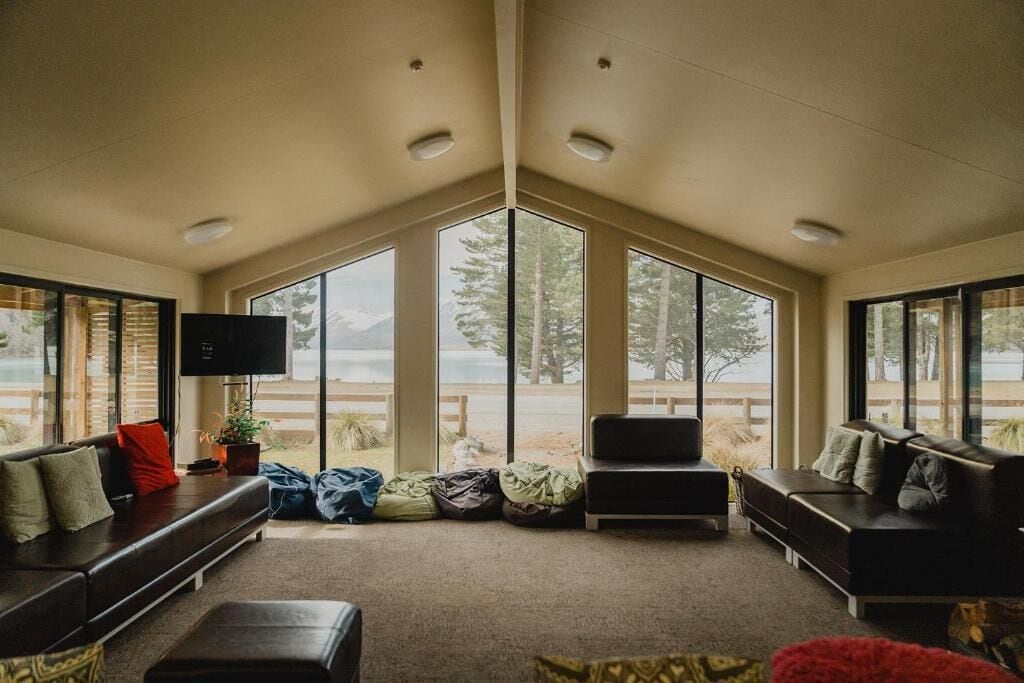 A modern living room with large windows, a flat-screen TV, and a sofa.