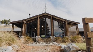 A modern building with large glass windows, a wooden structure, and a stone foundation. - Lakes Edge Lodge (Lake Tekapo)