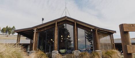 Un edificio moderno con amplios ventanales de vidrio, estructura de madera y base de piedra.