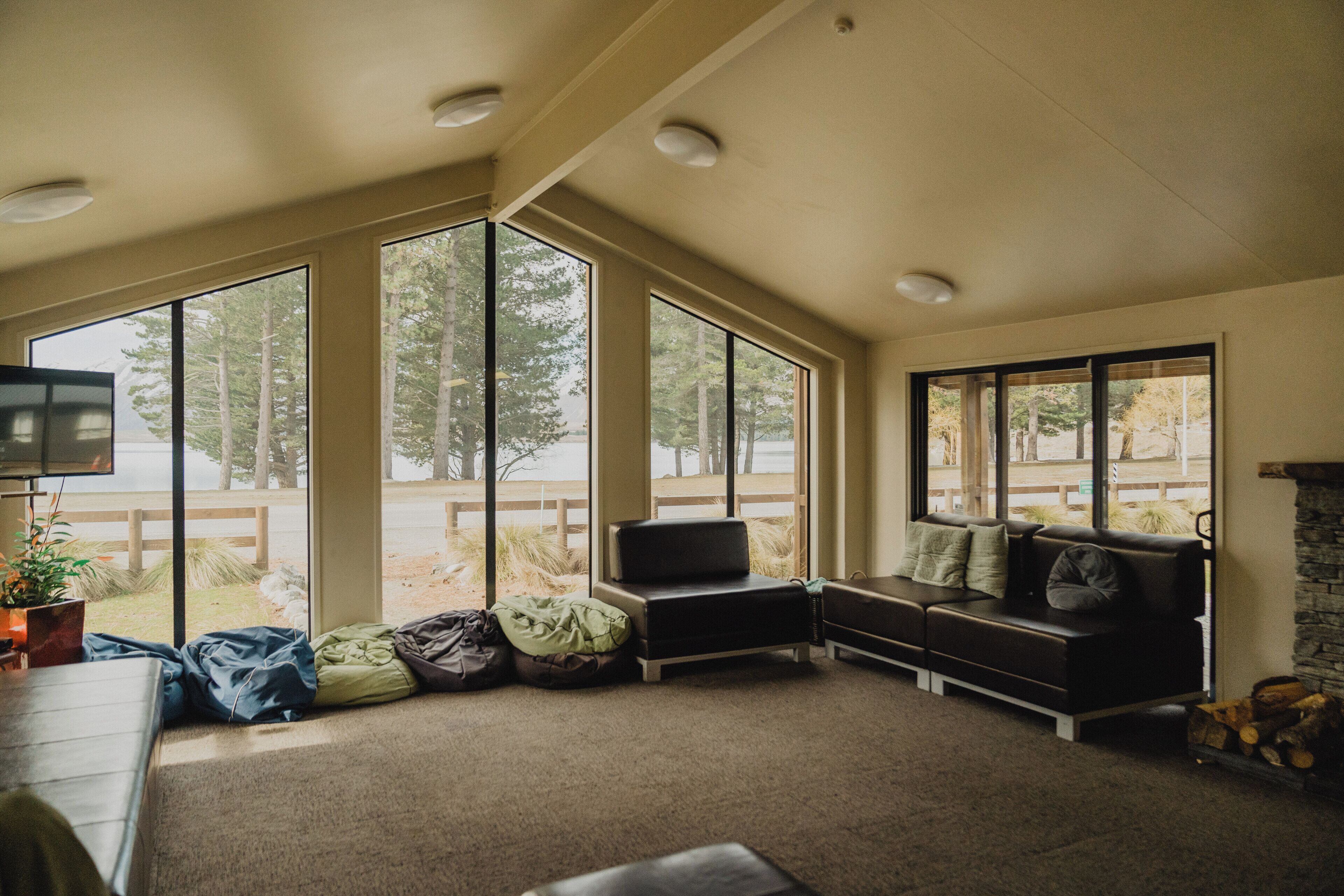 A room with large windows, a sofa, a television, and a fireplace.