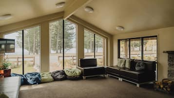 Una habitación con ventanas amplias, un sofá, una televisión y una chimenea.