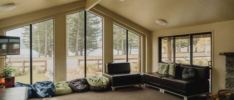 A room with large windows, a sofa, a television, and a fireplace.