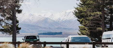 A covered outdoor seating area with a view of mountains and a lake.