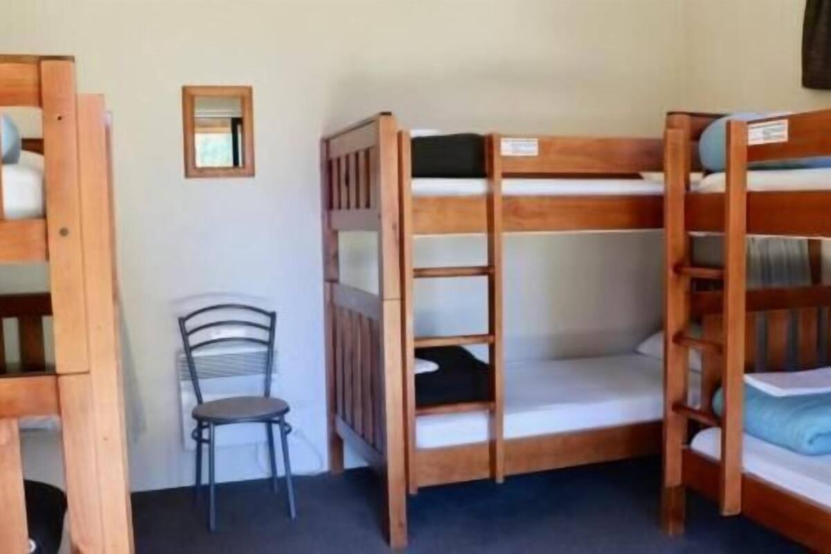 A bunk bed room with a chair and a small mirror.
