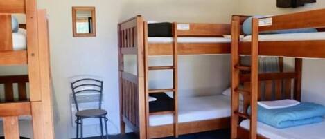 Dormitorio con literas, una silla y un pequeño espejo.