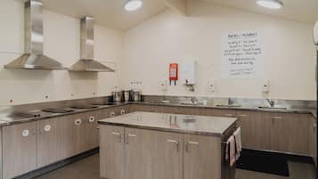 Uma cozinha com eletrodomésticos de aço inoxidável, armários de madeira e um aviso com as regras da cozinha.