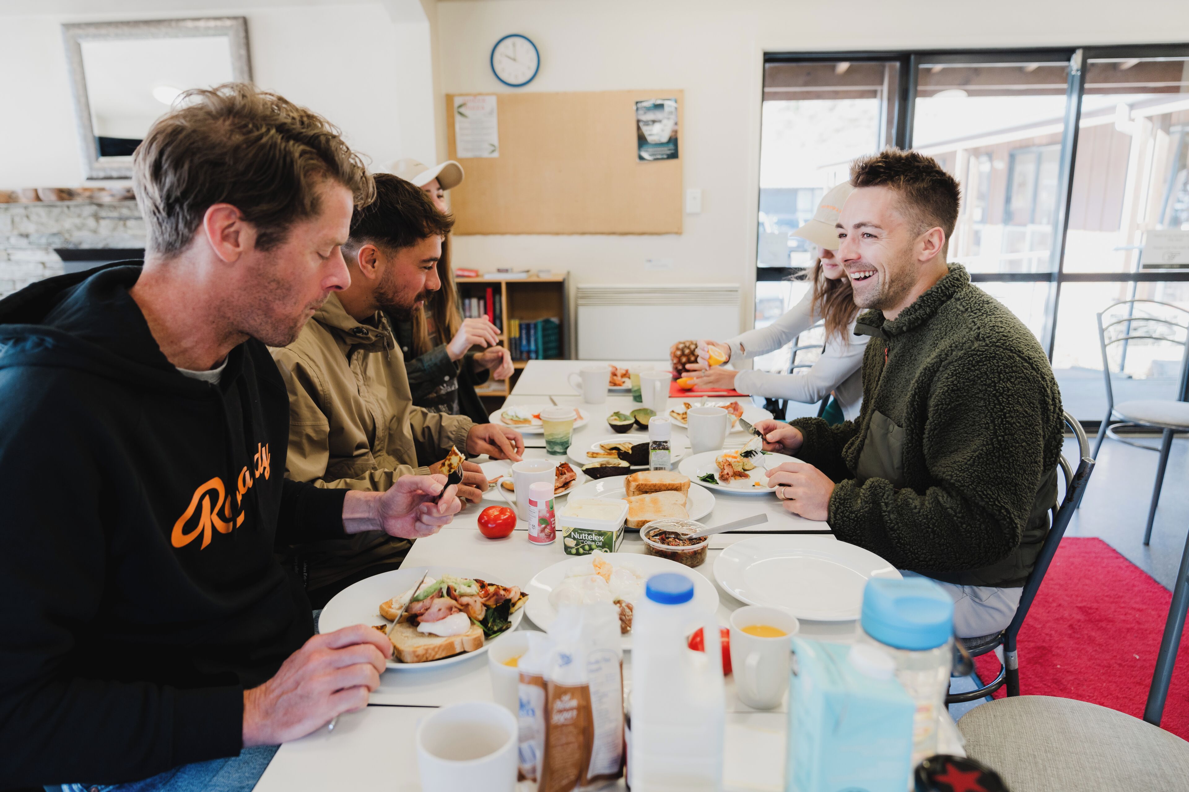 A group of people dining at a table with various food items and drinks.