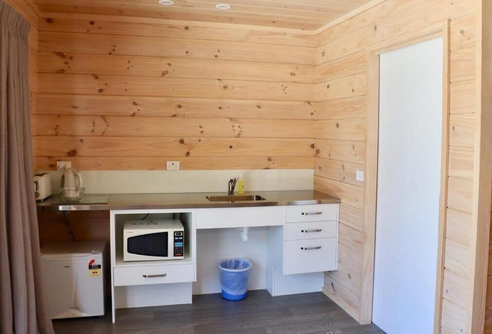 A compact kitchen with a microwave, sink, and storage cabinets.