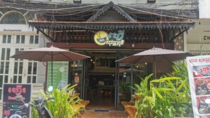 A restaurant with a signboard, outdoor seating, and a scooter parked in front. - Sovanphum Riverside Hotel (Phnom Penh)