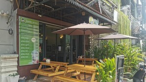 A restaurant with outdoor seating, a menu board, and a scooter parked nearby. - Sovanphum Riverside Hotel (Phnom Penh)